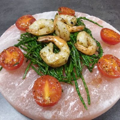 Scampis auf Salicornia mit Kirschtomaten auf heißer Salzplanke