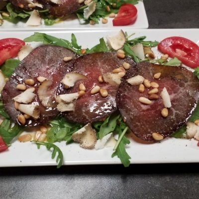 Wagyu Bresaola Carpaccio auf Ruccola mit Parmegiano Reggiano und gerösteten Pinienkernen